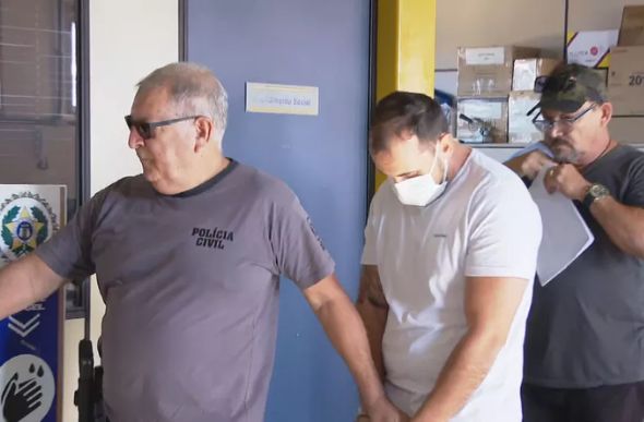 O médico Giovanni Quintella Bezerra foi levado algemado da Deam de São João de Meriti, na Baixada Fluminense, na manhã de segunda-feira (11) — Foto: Reprodução/ TV Globo