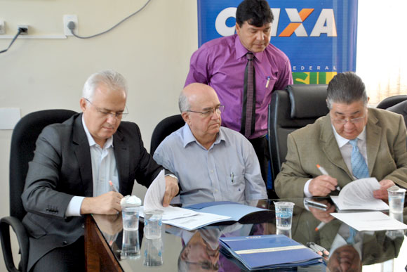 Observados por Marcio Paulino (de pé) e Joedes Marques (sentado ao centro), José Geraldo Sales e Marcio Reinaldo assinam os contratos / Foto: Marcelo Paiva 